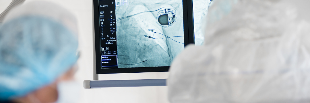 Surgeon looking at x-ray monitor displaying image of a pacemaker on the screen 